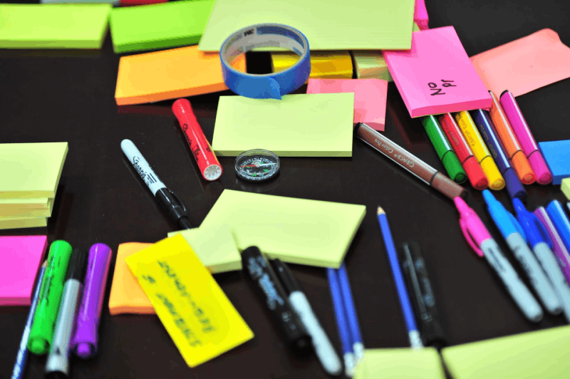 Grafiika z notesami, długopisami symbolizujące kreatywność, zarządzanie